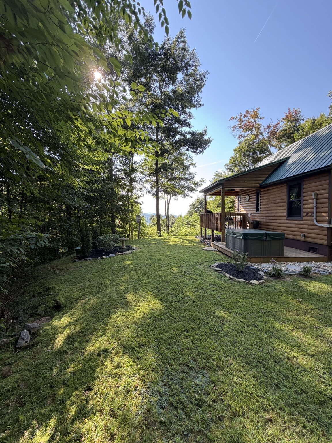 Freshly maintained lawn beside a mountain vacation cabin and hot tub